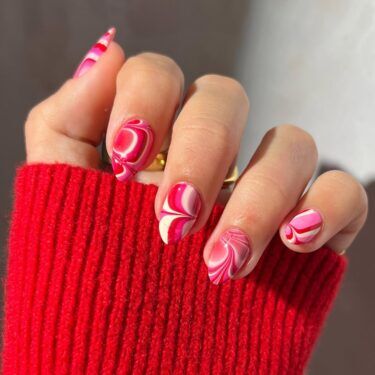 A water marble manicure with pink, red and white colors
